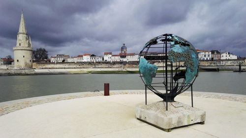 Gazebo in river by buildings against sky in city