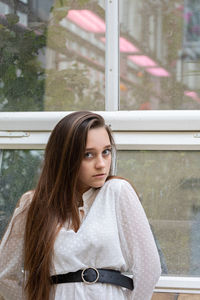 Portrait of young woman looking through window