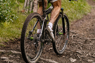 Low section of man riding bicycle on dirt road