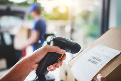 Cropped hand scanning bar code with reader in warehouse