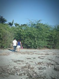 Rear view of man and woman walking against trees