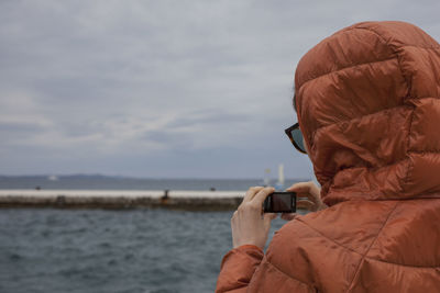 Portrait of a person photographing sea against sky