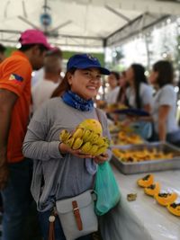 Happy mid adult woman with fruits standing at market