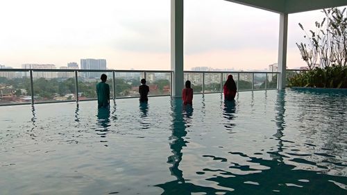 People standing by swimming pool against sky