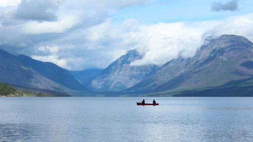 People sailing in lake against mountains 