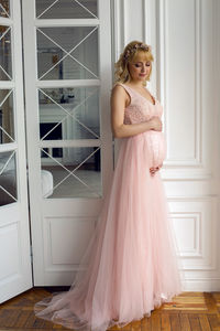 Portrait of a pregnant blonde woman with long hair in the studio in a dress