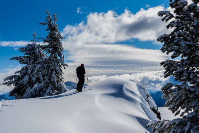 Person standing on snowcapped mountain against sky