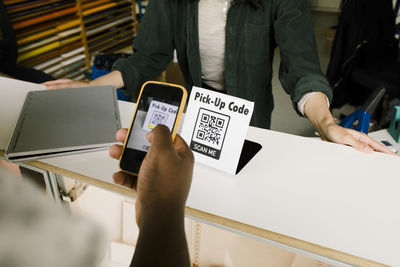 High angle view of man scanning bar code while doing online payment at repair shop