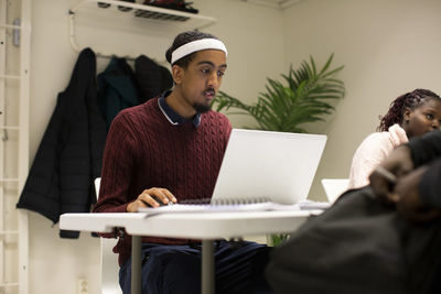 Young student using laptop while sitting in classroom