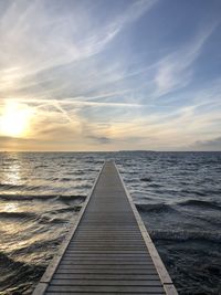 Pier over sea against sky during sunset