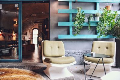 Empty chairs and tables against wall by doorway at home