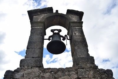 Low angle view of bell tower against clouds