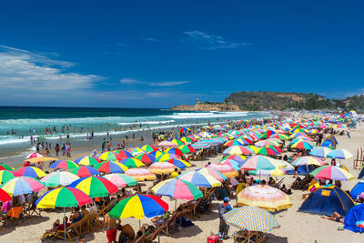 People and colorful parasols at beach during sunny day