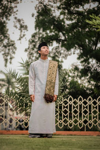 Portrait of young man standing against plants