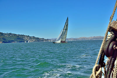 Sailboats sailing on sea against clear blue sky