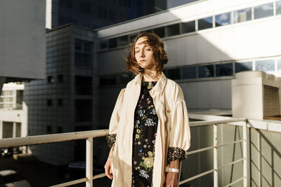 Woman looking away while standing against railing