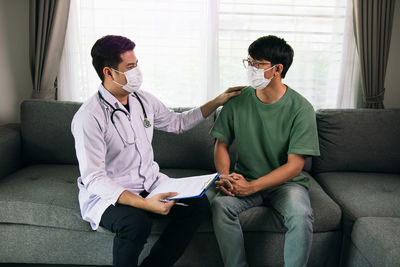 Doctor wearing mask consoling patient at clinic