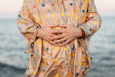 Midsection of man wearing raincoat at beach