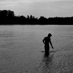 Silhouette man standing in lake against sky