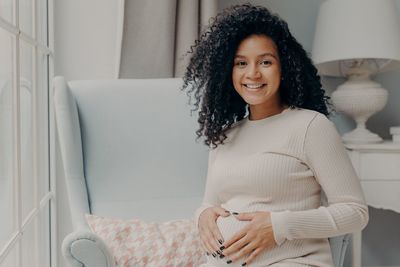 Portrait of smiling young woman sitting at home