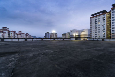 Buildings by street against sky at dusk