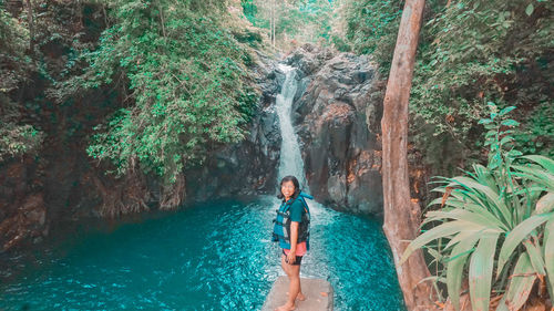 Woman in waterfall amidst trees