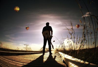 Silhouette of woman standing against sky at sunset