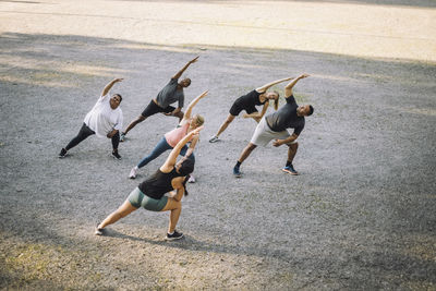 High angle view of female coach doing stretching with team at park