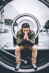 Young man sitting on sea at city street