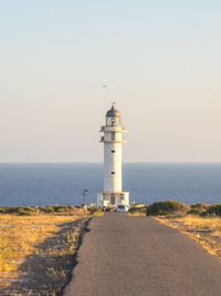 Lighthouse by sea against clear sky
