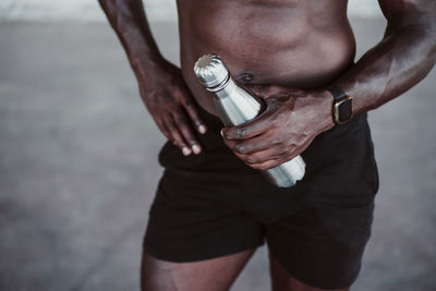 Male athlete holding water bottle while standing outdoors