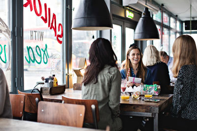 Smiling female friends enjoying while sitting at dining table for brunch in restaurant