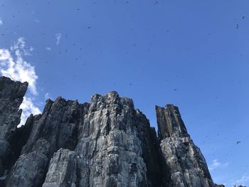 Low angle view of rocks against blue sky