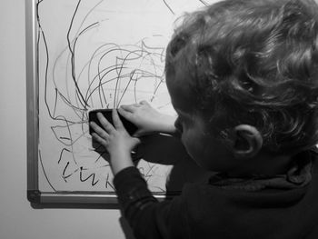 Cropped image of girl scribbling on white board