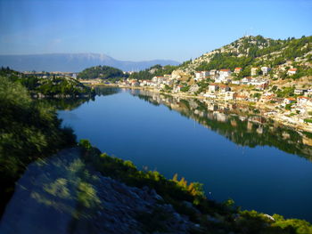 Scenic view of river amidst buildings against blue sky