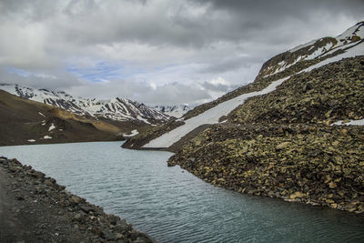 Scenic view of river by snowcapped mountains against sky
