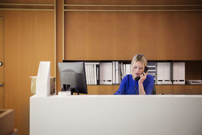 Businesswoman talking on telephone at desk in office