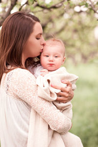 Mother carrying baby boy wrapped in blanket