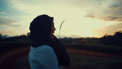 Side view of man standing on field against sky