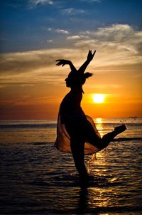 Silhouette woman on beach against sky during sunset