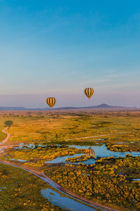 Hot air balloons flying over landscape against sky