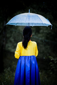 Portrait of woman with umbrella standing in forest