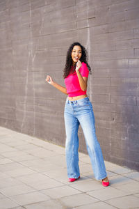 Portrait of young woman standing against wall