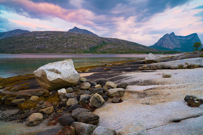 Rocks by lake against sky