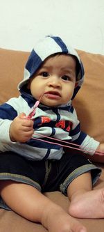 Portrait of cute baby girl sitting on sofa