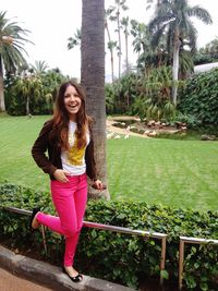 Portrait of smiling young woman standing against trees