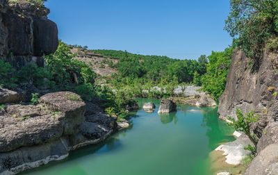 Scenic view of rock formation amidst trees against sky