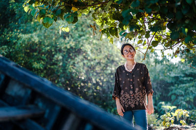 Portrait of smiling young woman standing against trees