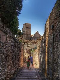 Rear view of people walking on historical building against sky