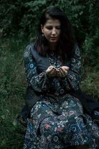 Young woman crouching on grassy field in forest